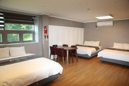 a room with two beds and a table and chairs at Mungang Hot Springs Hotel in Chungju