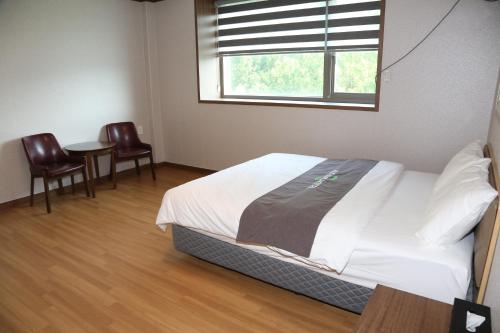 a bedroom with a bed with two chairs and a table at Mungang Hot Springs Hotel in Chungju