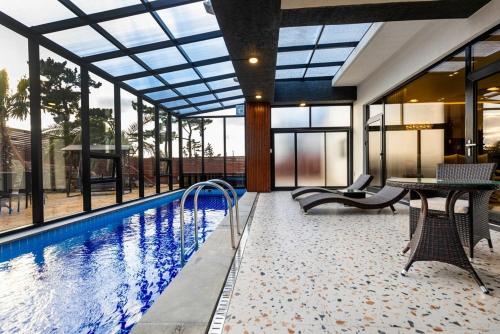 a house with a swimming pool with a table and chairs at Jeju Mare Private Pool Villa in Jeju