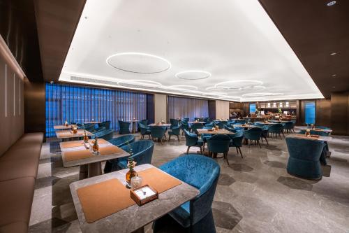 une salle à manger avec des tables et des chaises bleues dans l'établissement Crystal Hotel Qingdao The Mall of Splendors, à Qingdao