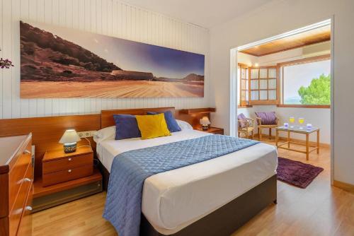 ein Schlafzimmer mit einem Bett und einem großen Gemälde an der Wand in der Unterkunft Delightful Ibiza Villa Spectacular Mountain Views Villa Jasmine in Sant Rafael de Sa Creu