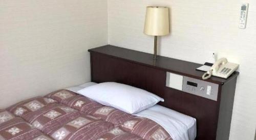 a hotel room with a bed and a telephone at Hotel Town Nishikigawa in Kochi