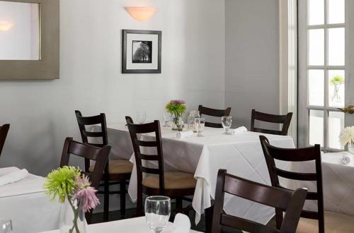 a dining room with white tables and chairs with flowers on them at Shelter Island House in Shelter Island Heights