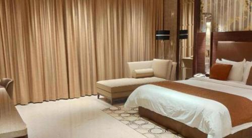 a hotel room with a large bed and a chair at Jai Alai Hotel in Macau
