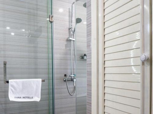 a shower with a white towel on a glass door at Xana Lite Anqing Yuexi Swan Squre Branch in Yuexi
