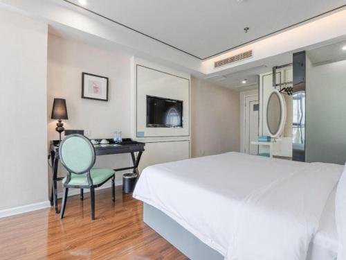 a bedroom with a bed and a desk with a chair at Xana Lite Anqing Yuexi Swan Squre Branch in Yuexi