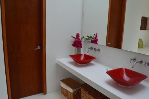 Baño con 2 lavabos rojos y espejo en Casa Anapoima Kubik Aqua, en Anapoima