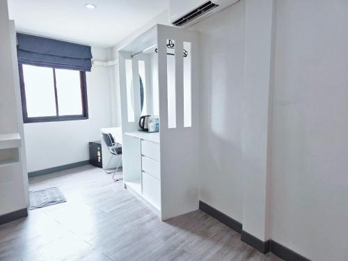a white room with a desk and a mirror at Ma Non Nont Hotel & Apartment in Nonthaburi