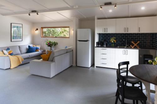 a living room with a white couch and a kitchen at Garden Beds Glamping in Blackwood