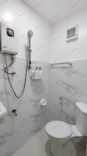 a white bathroom with a toilet and a shower at Tokai's Transient House in Legazpi
