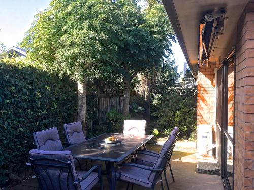 a table and chairs on a patio with a tree at Mount Maunganui House -Walk to Beach, Shops, Cafés in Mount Maunganui