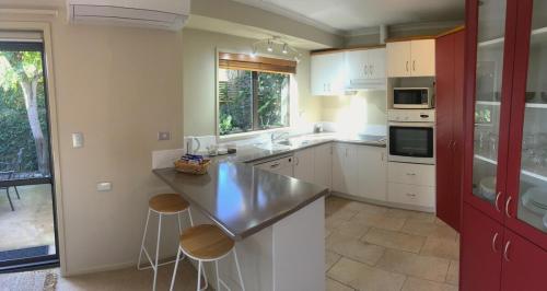 a kitchen with white cabinets and a counter with stools at Mount Maunganui House -Walk to Beach, Shops, Cafés in Mount Maunganui
