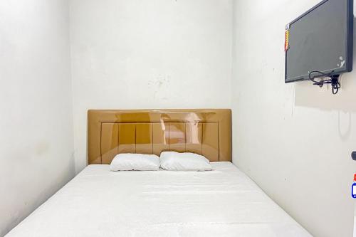 a bed with two pillows in a room with a tv at Guest House 21 RedPartner in Jakarta