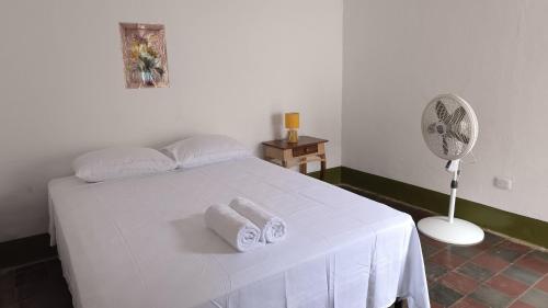 a bedroom with a white bed with towels and a fan at Casa Girasol in Granada
