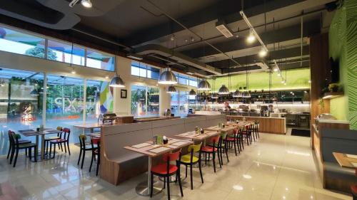 a restaurant with tables and chairs and a kitchen at Zuri Express Lippo Cikarang in Cikarang