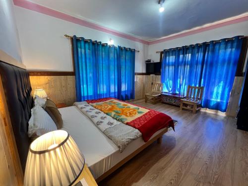 a bedroom with blue drapes and a bed with avertisement at Sky Land guest house in Leh