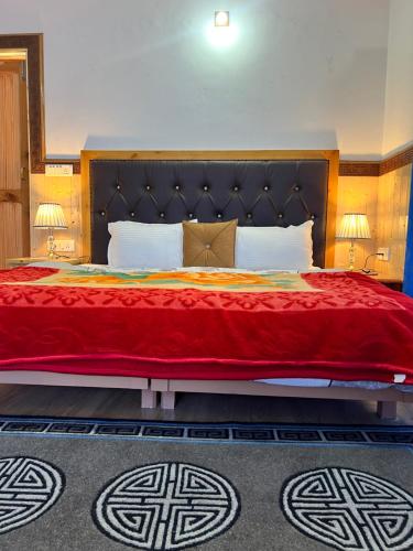 a bedroom with a large bed with a red blanket at Sky Land guest house in Leh
