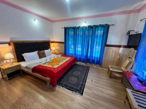 a bedroom with a bed with a red blanket and blue curtains at Sky Land guest house in Leh