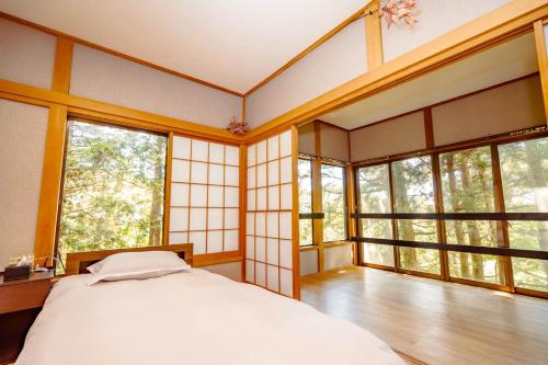 a bedroom with a bed in a room with windows at 箱根 望森荘 in Hakone