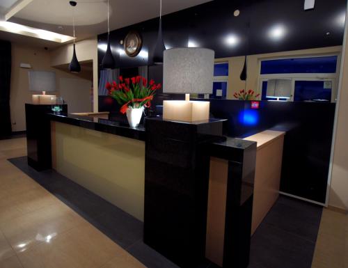 a lobby with a counter with flowers and a clock at Hotel Hibiskus in Boguchwała