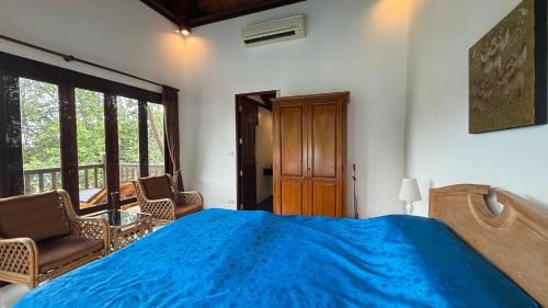 a bedroom with a blue bed and chairs and windows at CM8 Beds & Private Pool in Mae Pim