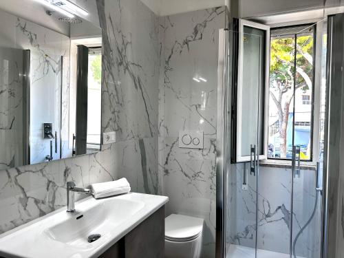 a white bathroom with a sink and a shower at Fontana apartment in Lignano Sabbiadoro