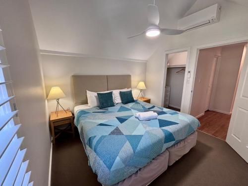a bedroom with a blue and white bed and two lamps at Escape to 67 at Cape View in Broadwater
