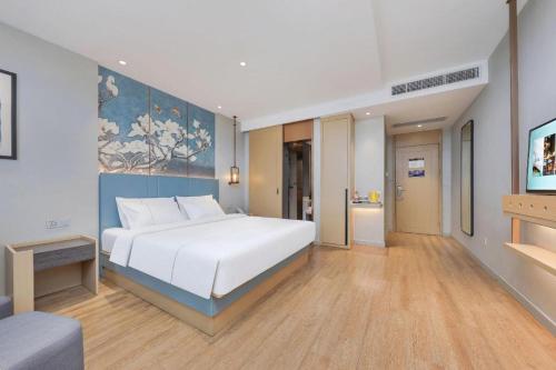 a bedroom with a white bed and a blue wall at Magnotel Hotel Xiamen North Station Binhai in Xiamen