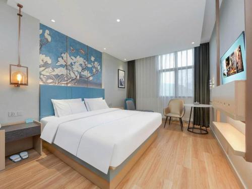 a bedroom with a large white bed and a desk at Magnotel Hotel Xiamen North Station Binhai in Xiamen