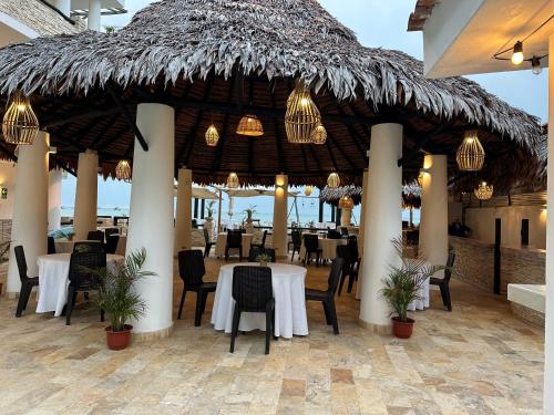 a restaurant with tables and chairs and a thatched roof at Mango & Apartments in Tumbes