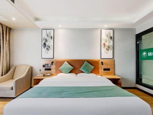 a bedroom with a bed and a chair and a window at GreenTree Inn Anqing Yingbin Dong Road High-Speed Railway Station in Anqing