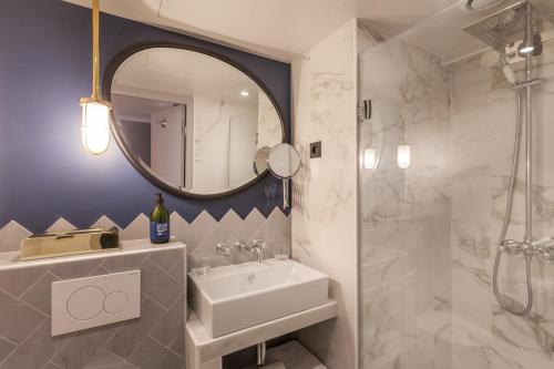 uma casa de banho com um lavatório, um chuveiro e um espelho. em Handsome Hotel em Paris