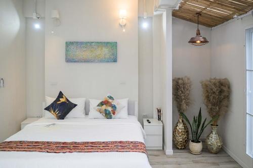 a white bedroom with a bed and a painting on the wall at Coconut Breeze Villa 3 in Haad Chao Phao