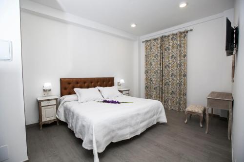 a white bedroom with a large bed and a desk at Hostal Boutique Bajamar in Nerja