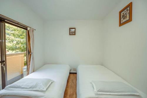 two beds in a room with a window at 山崎公園-箱根湯本駅-最大8名 in Hakone