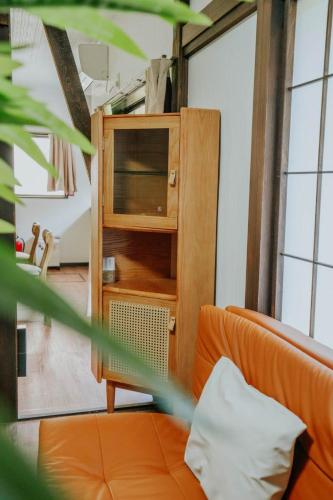 a room with an orange couch and a wooden cabinet at 山崎公園-箱根湯本駅-最大8名 in Hakone