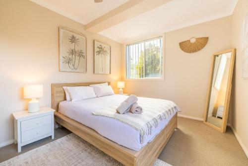 a bedroom with a bed with a teddy bear laying on it at Magnolias, 6 Marine Dr - air con, linen and Wi-Fi in Fingal Bay