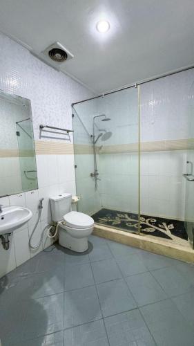 a bathroom with a toilet and a glass shower at Dedy Beach Inn in Kuta