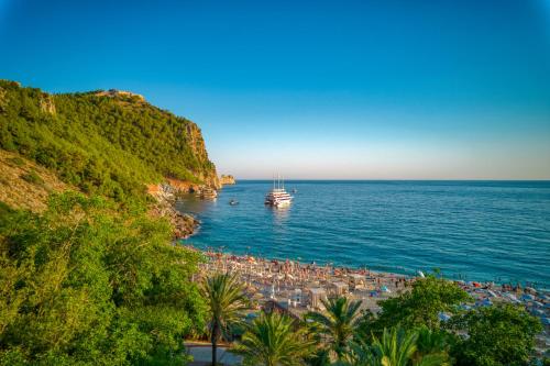 a beach with umbrellas and a boat in the water at La Gaia - Adult Only in Alanya