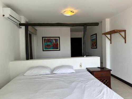 a bedroom with a white bed and a wooden table at Mango & Apartments in Tumbes