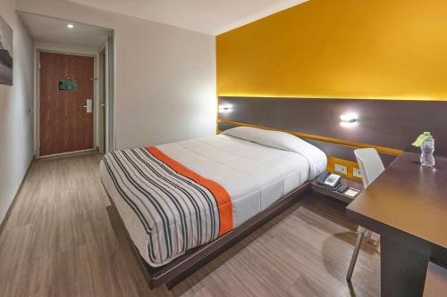 a hotel room with a bed and a desk at City Express Junior by Marriott Mexicali in Mexicali