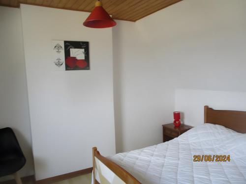 a bedroom with a white bed and a red lamp at Gîte Vue Imprenable Mer in Lanmodez