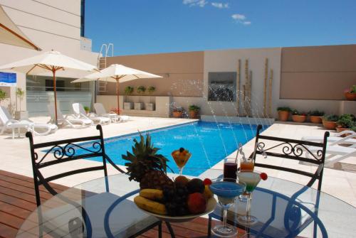 a table with a bowl of fruit next to a pool at Howard Johnson Villa María Hotel y Casino in Villa María