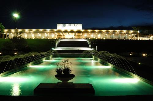 un edificio iluminado por la noche con una fuente en Howard Johnson Sierras Hotel y Casino Alta Gracia en Alta Gracia