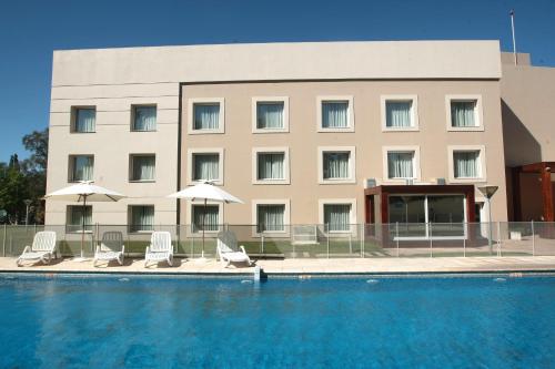 ein Hotel mit einem Pool mit Stühlen und Sonnenschirmen in der Unterkunft Howard Johnson Rio Cuarto Hotel y Casino in Río Cuarto