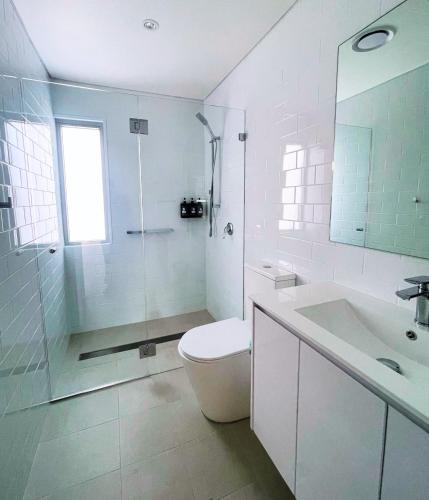 a white bathroom with a toilet and a sink at Resort on Cedar in Windang