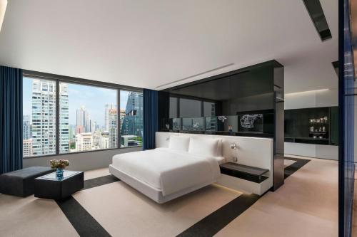 a bedroom with a white bed and large windows at W Bangkok Hotel in Bangkok