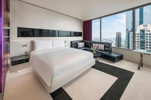 a bedroom with a large white bed and a couch at W Bangkok Hotel in Bangkok