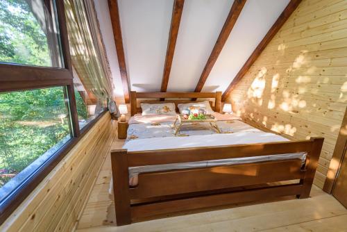 a bed in a wooden room with windows at Mountain harmony Lovćen in Cetinje