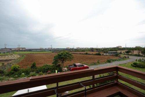 a red car parked on a road in a field at Jeju Aneuk Stay in Murŭng-ni